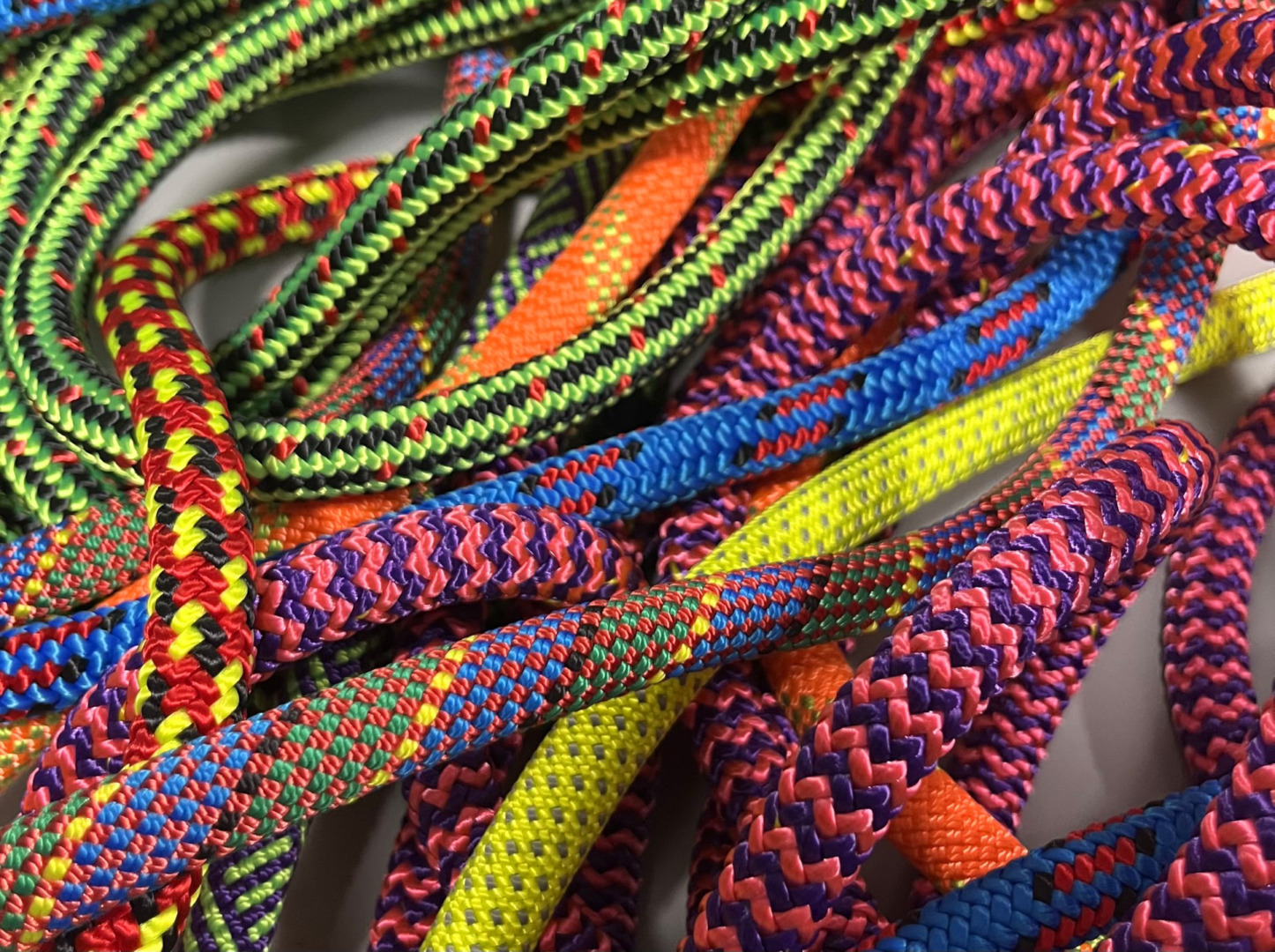 Close-up of vibrant, colorful ropes tangled together in various patterns and textures on a white surface