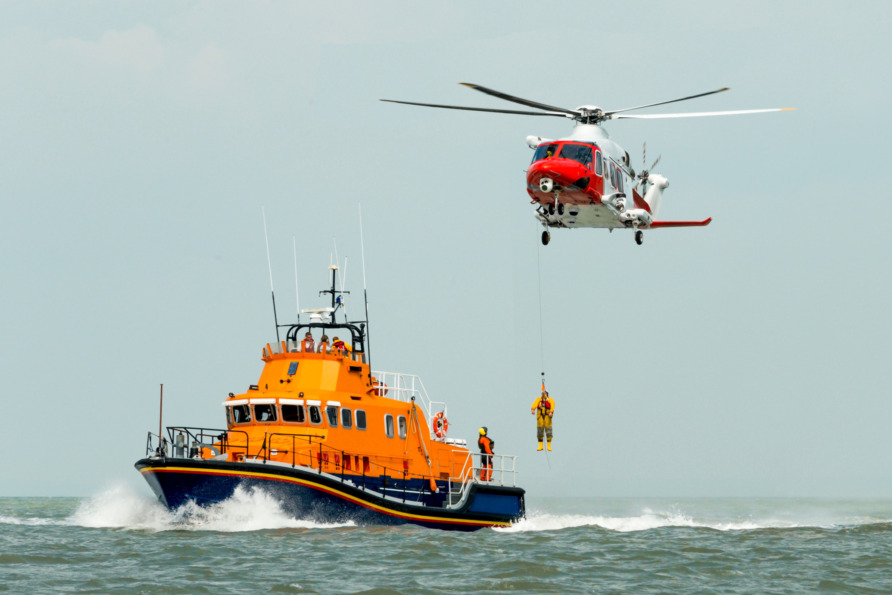 Coast guard rescue operation with helicopter and lifeboat in action on the ocean.