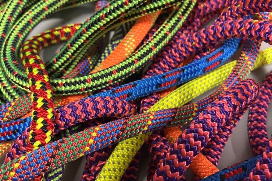 Close-up of colorful climbing ropes intertwined, showcasing vibrant patterns and textures in red, yellow, blue, and green.