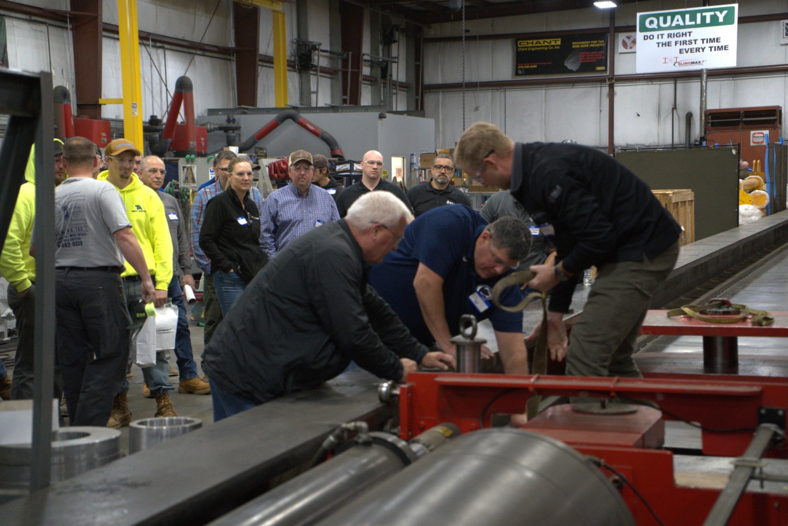 Group of people in a workshop observing machinery operation and safety demonstration in an industrial setting.
