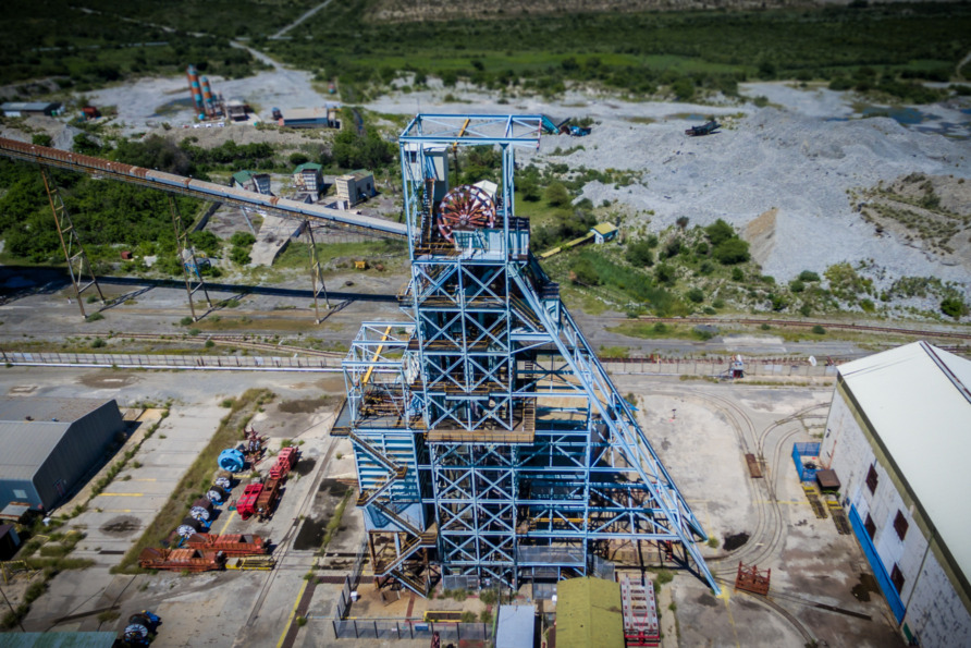 Aerial view of an industrial mining structure with surrounding greenery and equipment.