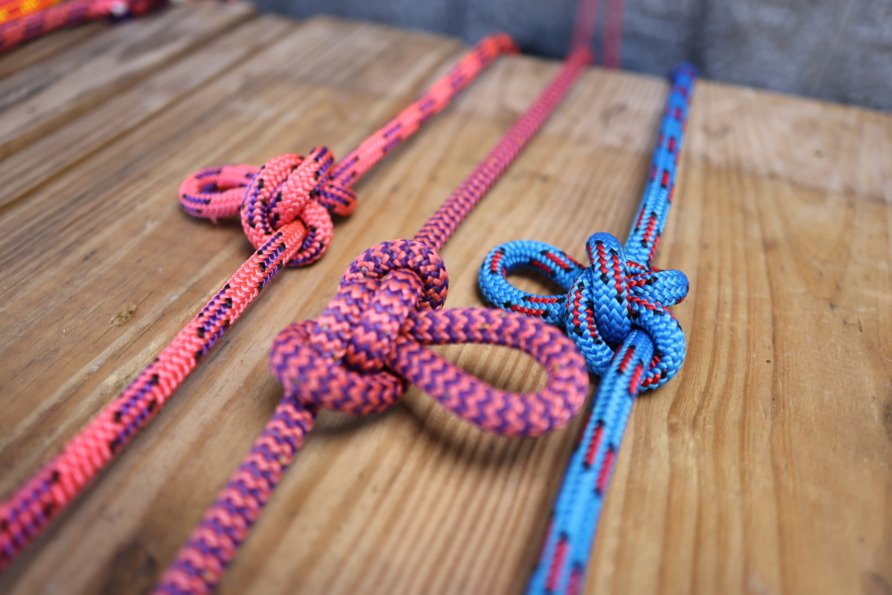 Close-up of colorful climbing ropes with knots on a wooden surface.