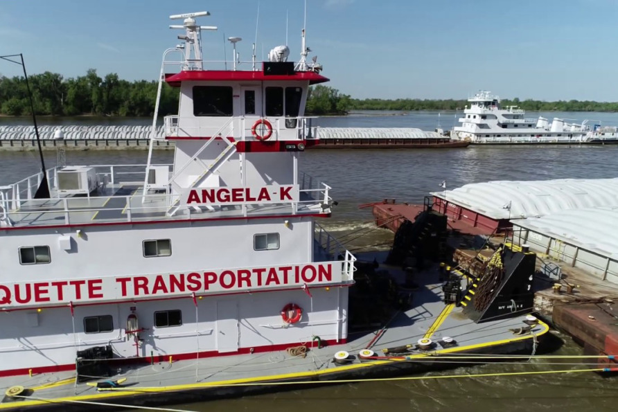 Tugboat "Angela K" from Marquette Transportation pushing a barge on a river with another boat in the background.