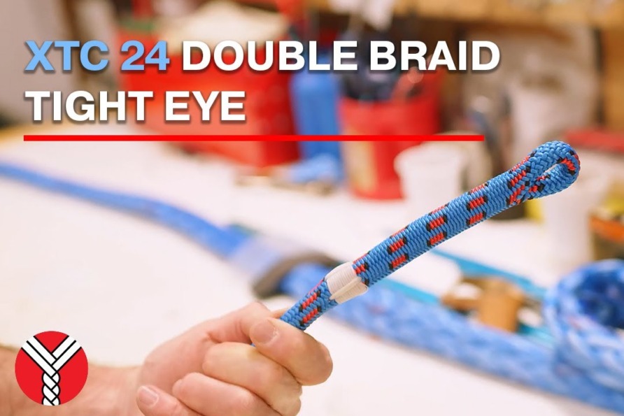 Person holding a blue and red braided rope with a looped end on a workshop table.