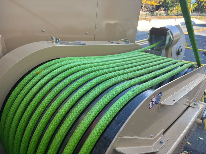 Green rope wound around a machine on a sunny day.