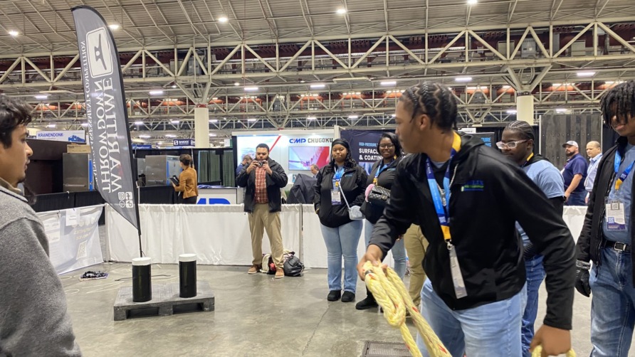 Group of people in a convention center, some interacting with a rope in an activity area.