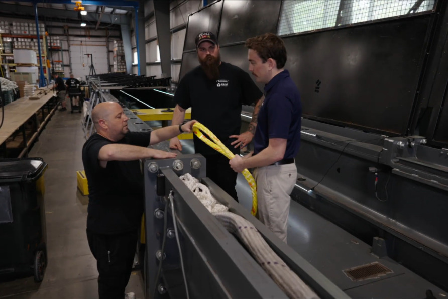 Three men working together on industrial equipment in a manufacturing facility.