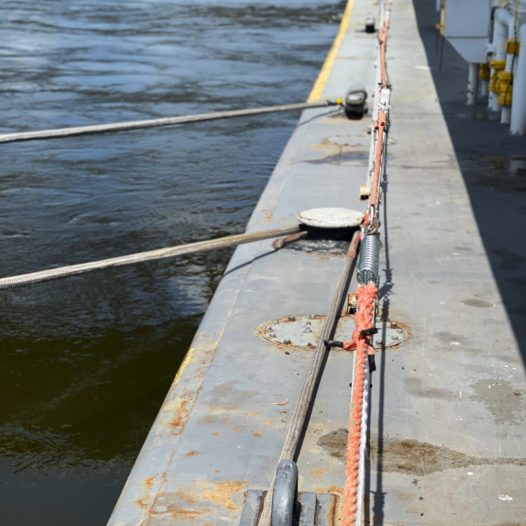 Ropes and cables secured on a metal dock by the water.